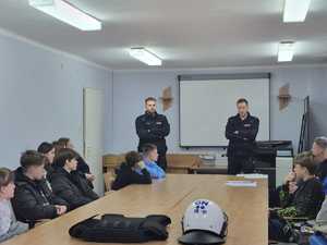 umundurowani policjanci w sali przed nimi siedzą uczniowie w ławkach