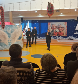 umundurowana policjantka i dwóch policjantów w sali przed nimi siedzą seniorzy