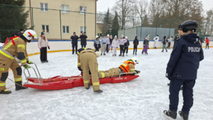 strażacy i policjantka podczas zajęć na lodowisku