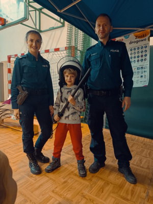 policjant i policjantka z nimi chłopiec w ubraniu policyjnym