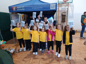 policjantka i grupa dzieci którzy trzymają ulotki