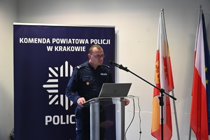 policjant w mudnurze przemawia stojąc za mównicą