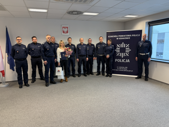 umundurowani policjanci i kobieta w ubraniu cywilnym pozują do wspólnego zdjęcia