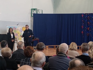 policjant w mundurze przed nim na sali siedzą seniorzy