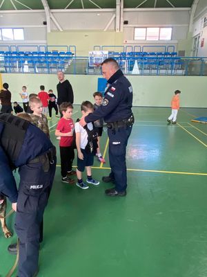 policjant w mundurze zakłada dziecku policyjną kamizelkę