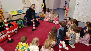 policjant w mundurze przed nim siedzą przedszkolaki