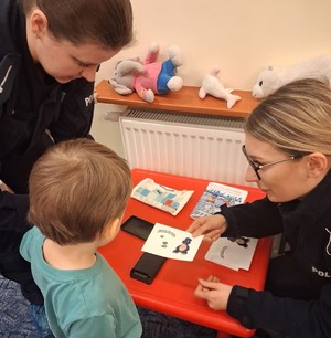 dwie umundurowane policjantki wręczają ulotkę dziecku