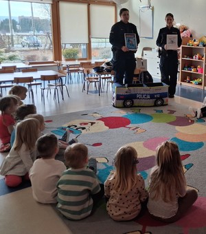 umundurowane policjantki przed nimi dzieci na dywanie