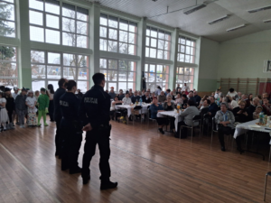 policjanci umundurowani na sali przed nimi siedzą seniorzy