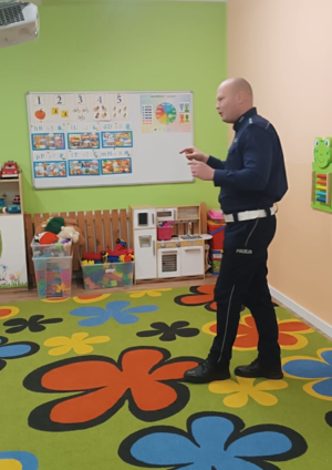policjant w mudurze podczas prelekcji w sali przedszkolnej