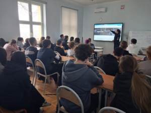 policjantka w mundurze w klasie przed nią siedzą w ławkach uczniowie