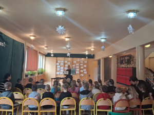 policjantka w mundurze przed nią siedzą dzieci na sali podczas prelekcji