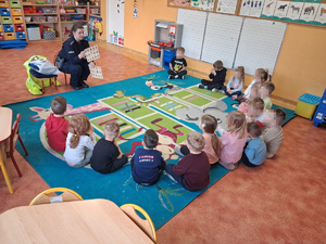 policjantka w mundurze przed nią siedzą dzieci na dywanie