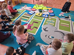 dzieci siedzą na dywanie w sali