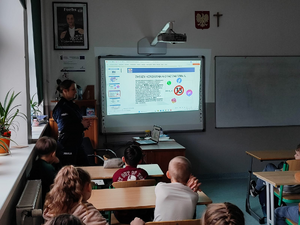 policjantka w mundurze w sali przed nią siedzą uczniowie w ławkach