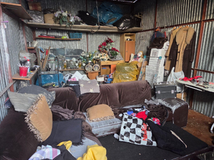 wnętrze blaszanego garażu, sofa, wiszące ubrania, półki, ogólny bałagan