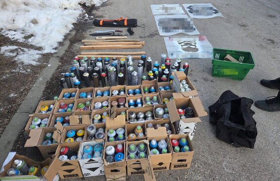 farby w spray w pudełkach, za nimi leżą maczety i szablony do malowania