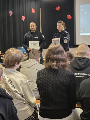 policjantka i policjant podczas prelekcji przed nimi uczniowie