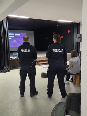 policjantka i policjant w mundurach stoją przodem do ekranu
