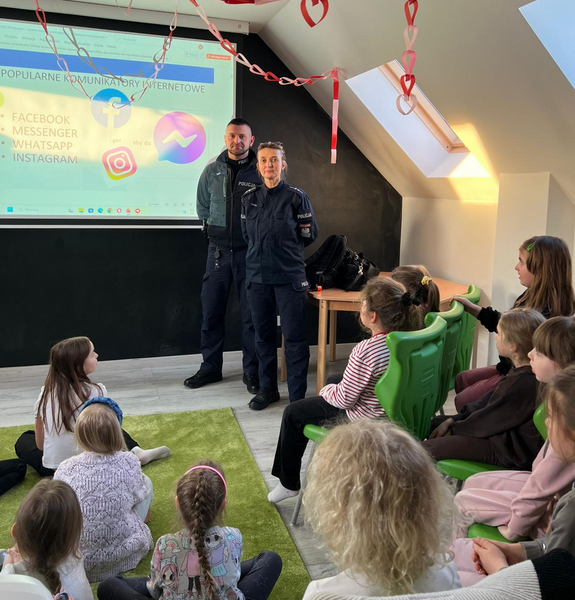 policjantka i policjant w mundurach podczas prelekcji przed nimi siedzą dzieci