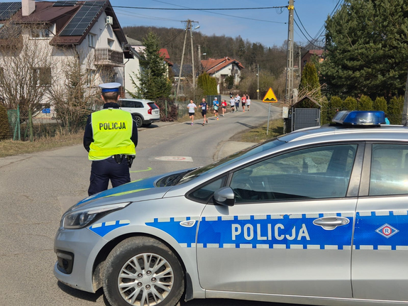 oznakowany radiowóz i policjantka w mundurze przy drodze