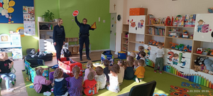 policjantki w mundurach pokazują dzieciom znaki drogowe, dzieci siedzą na dywanie