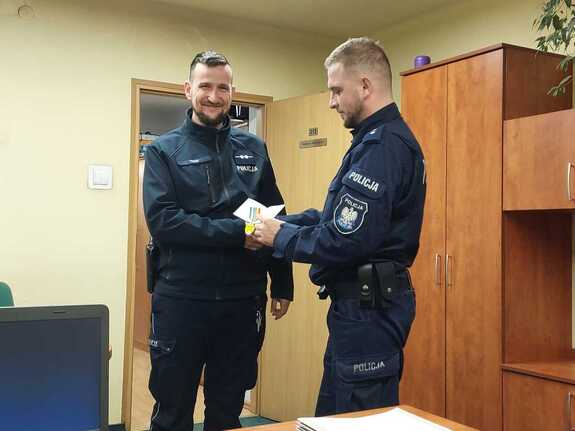 policjant w mudnurze wręcza drugiemu policjantowi medal