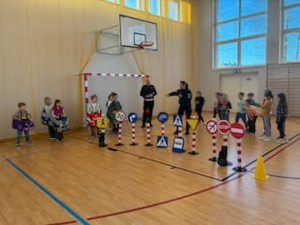 sala gimnastyczna, policjanci, uczniowie i rozstawione miasteczko bezpieczeństwa