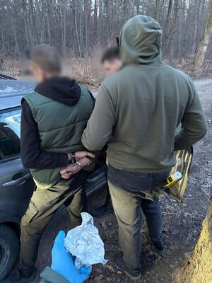 meżczzyna z rękami skutymi kajdankami i dwóch policjantów bez munduru