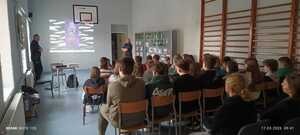 policjanci w mundurach podczas prelekcji w sali lekcyjnej przed nimi siedzą uczniowie