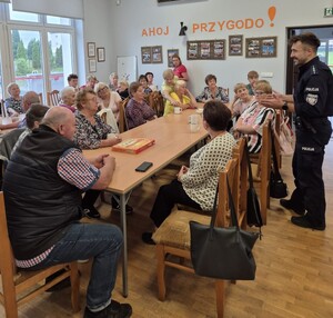 policjant z mundurze a przed nim siedzą seniorzy