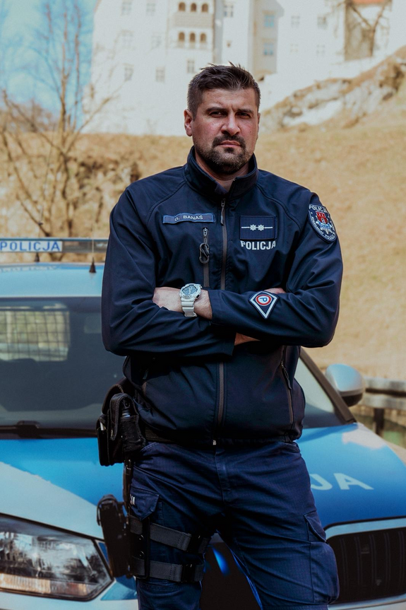 policjant w mundurze przed oznakowanym radiowozem