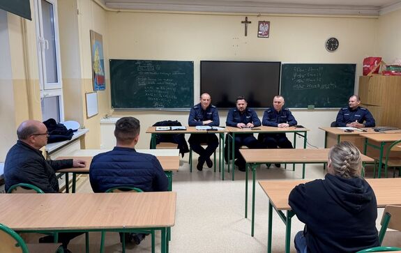 policjanci w mundurach siedzą w sali przed nimi uczestnicy debaty społecznej