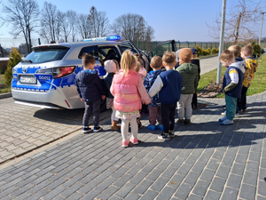 oznakowany radiowóz a przed nim dzieci