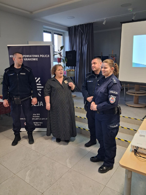 policjanci w mudnurach obok stoi kobieta podczas spotkania z seniorami