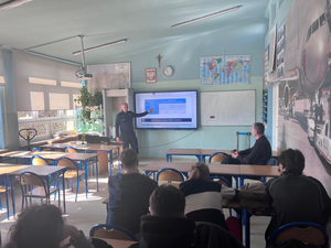 policjant w mundurze w klasie przy tablicy przed nim siedzą uczniowie w ławkach