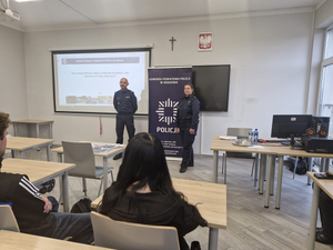policjanci w mundurach podczas prelekcji w sali lekcyjnej przed nimi siedzą w ławkach uczniowie