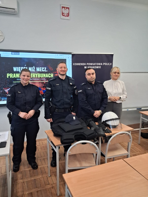 umundurowani policjanci z nauczycielką przed tablicą