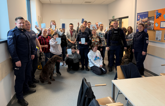 zdjęcie grupowe w komendzie z policjantami, uczestnikami i psami służbowymi