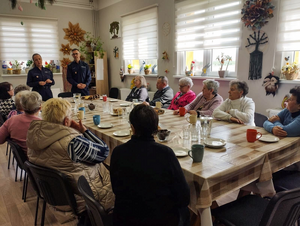 policjanci w mundurach w sali przed nimi siedzą seniorzy podczas prelekcji