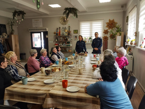 policjanci w mundurach przed nimi siedzą seniorzy w sali podczas spotkania