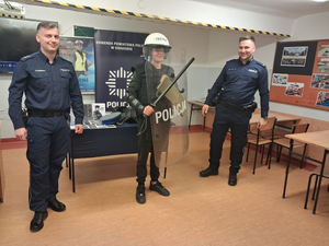 dwóch policjantów w mundurach i uczeń w ubraniu szturmowym policjanta