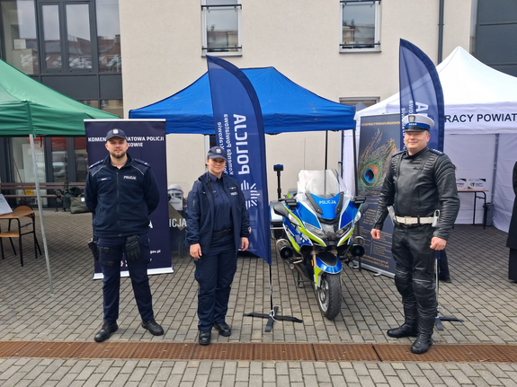 policjanci w mundurach przed namiotem obok policyjny motor