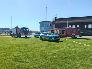 oznakowany radiowóz i wozy strażackie na terenie lotniska