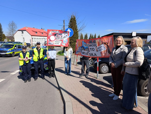 policjanci w mundurach obok uczniowie z transparentami podczas działań na ulicy