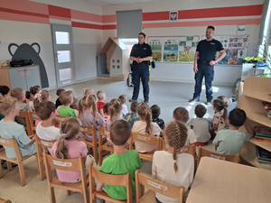 policjantka i policjant w mundurach w sali przed nimi siedzą przedszkolaki