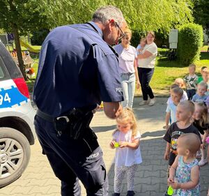 policjant w mundurze rozdaje dzieciom odblaski