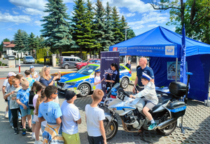 policyjny namiot a przed nim policyjny motor, policjanci w mundurach a przed nimi grupa dzieci