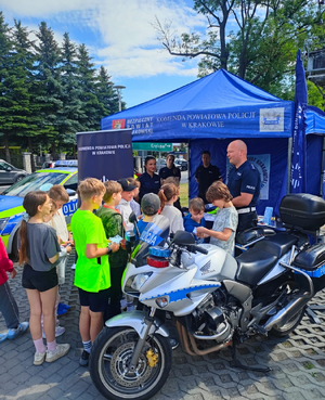 dzieci przed policyjnym namiotem obok motor policyjny i policjanci
