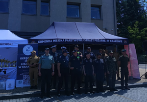namiot a przed nim policjanci i strażacy oraz przedstawiciele innych służb w mundurach